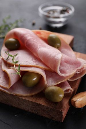 Tasty ham with olives, garlic and thyme on black table, closeupの写真素材