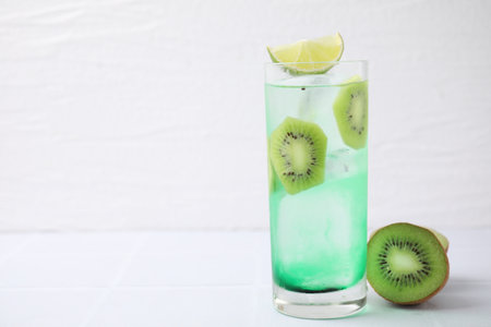 Glass of refreshing drink and cut kiwi on white table. Space for textの写真素材