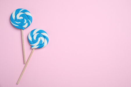 Sticks with bright lollipops on pink background, flat lay. Space for textの写真素材
