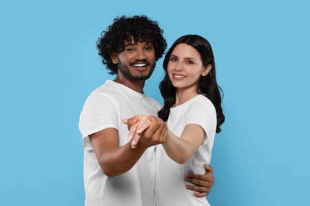 International dating. Happy couple dancing on light blue backgroundの写真素材