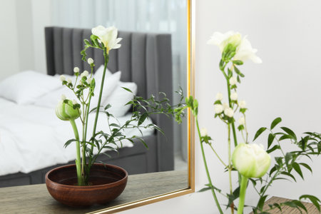 Stylish ikebana with beautiful flowers and green branch carrying cozy atmosphere at homeの写真素材