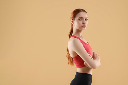 Young woman in sportswear on beige background, space for textの写真素材