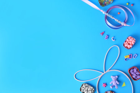 Kid`s handmade jewelry kit. Colorful beads, ribbon and supplies on light blue background, flat lay. Space for textの写真素材