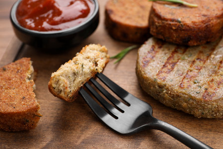 Fork with piece of delicious vegan cutlet on wooden table, closeupの写真素材
