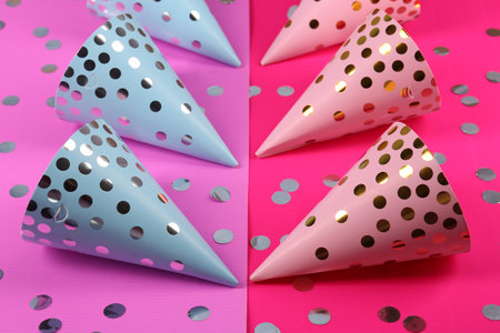 Bright party hats with confetti on color background. Handmade decorations