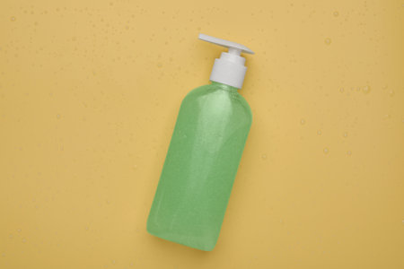 Wet bottle of face cleansing product on pale orange background, top viewの写真素材