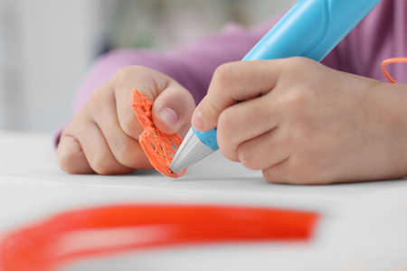 Girl drawing with stylish 3D pen at white table indoors, closeup