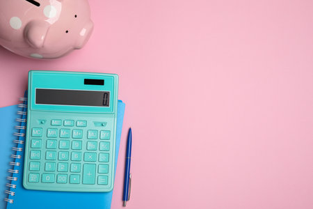 Calculator, piggy bank, notebooks and pen on pink background, flat lay with space for textの写真素材