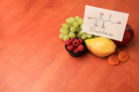 Card with word Fructose, delicious ripe fruits, raspberries and dried apricots on wooden table,...