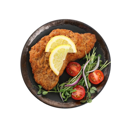 Plate of delicious schnitzels with lemon, tomatoes, onion and microgreens isolated on white, top viewの写真素材