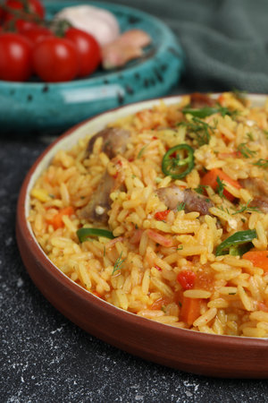 Delicious pilaf with meat and ingredients on black textured table, closeupの写真素材
