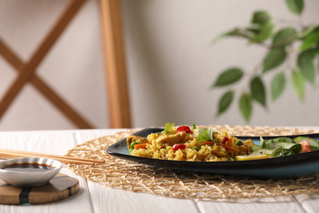 Tasty rice with meat and vegetables in plate served with soy sauce on white wooden table indoors. Space for textの写真素材