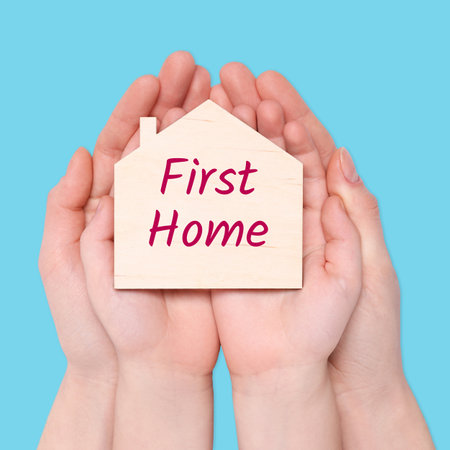 First time home buyer. Woman with her little child holding house figure on light blue background, top viewの写真素材