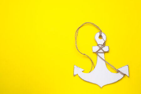 White wooden anchor figure on yellow background, top view. Space for textの写真素材