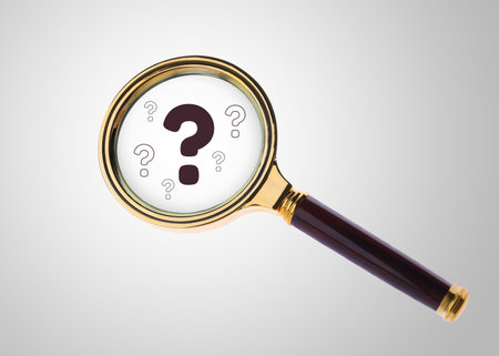Question marks on light background, view through magnifying glassの写真素材