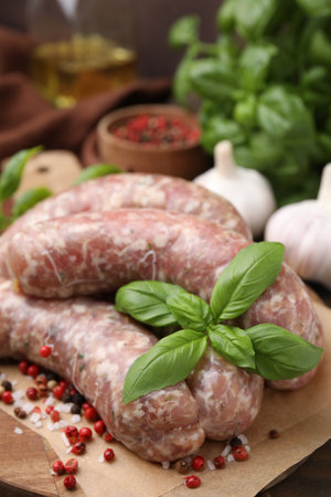 Raw homemade sausages and different spices on wooden board, closeupの写真素材