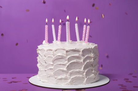 Delicious cake with cream and burning candles on purple backgroundの写真素材