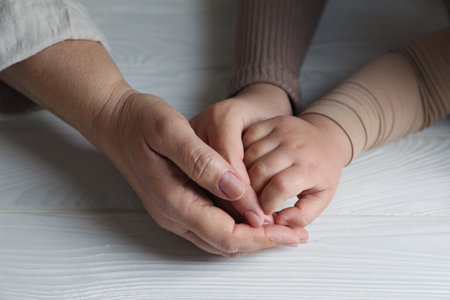Family holding hands together at white wooden table, closeupの写真素材