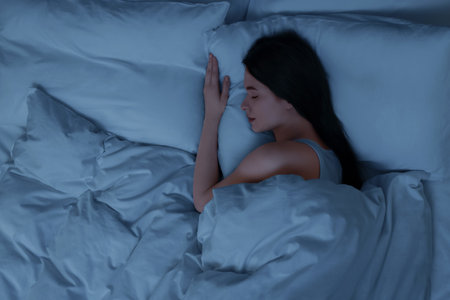 Beautiful young woman sleeping in bed at night, top viewの写真素材