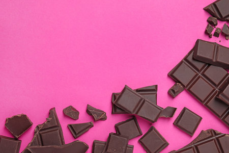 Pieces of delicious chocolate bars on pink background, flat lay. Space for textの写真素材