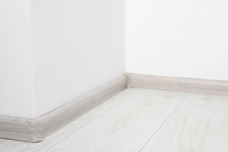 Wooden plinth with connectors on laminated floor near white wall indoorsの写真素材