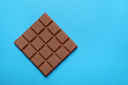 Delicious chocolate bar on light blue background, top view. Space for textの写真素材