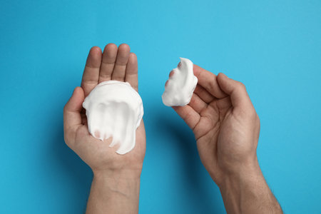 Man holding shaving foam on light blue background, top viewの写真素材