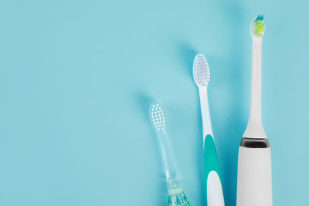 Electric toothbrushes on light blue background, flat lay, Space for textの写真素材