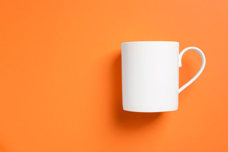One white ceramic mug on orange background, top view. Space for textの写真素材