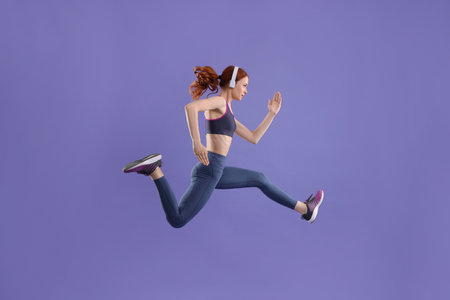 Woman in sportswear jumping on violet background, space for textの写真素材