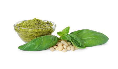 Delicious pesto sauce in bowl, pine nuts and basil leaves isolated on whiteの写真素材