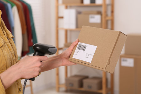 Seller with scanner reading parcel barcode in office, closeup. Online storeの写真素材