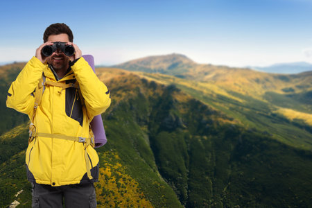 Tourist with backpack and binoculars in mountainsの写真素材