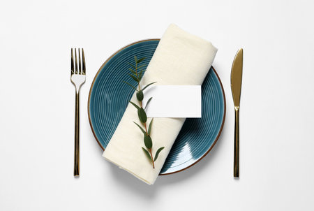 Stylish table setting with cutlery, blank card and eucalyptus leaves on white background, flat layの写真素材