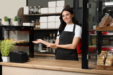 Business owner near showcases with desserts in her cafeの写真素材