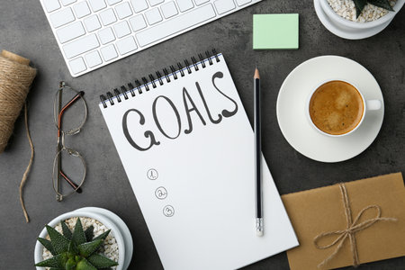 Planning concept. Empty list of goals in notebook, keyboard and coffee on gray table, flat layの写真素材
