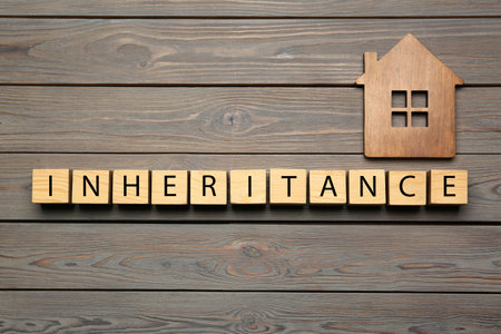 Word Inheritance made with cubes and house model on wooden background, flat layの写真素材