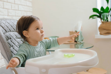 Cute little baby sitting in high chair indoorsの写真素材