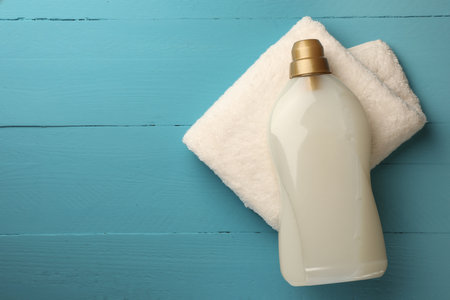 Bottle of fabric softener and terry towel on light blue wooden table, top view. Space for textの写真素材