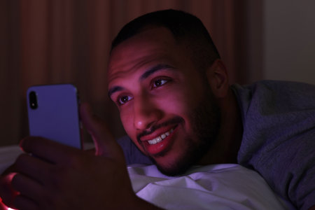 Young man using smartphone in bed at night. Internet addictionの写真素材