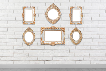 Blank vintage frames hanging on white brick wall. Mockup for designの写真素材