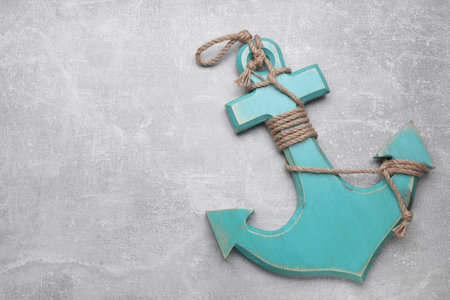 Wooden anchor with hemp rope on light gray table, top view. Space for text