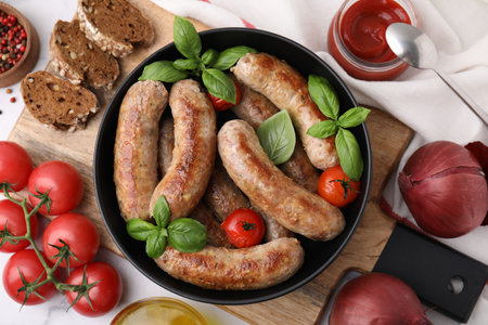 Flat lay composition with tasty homemade sausages, basil leaves and tomatoes in bowl on tableの写真素材