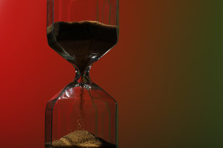 Hourglass with flowing sand on color background. Space for text