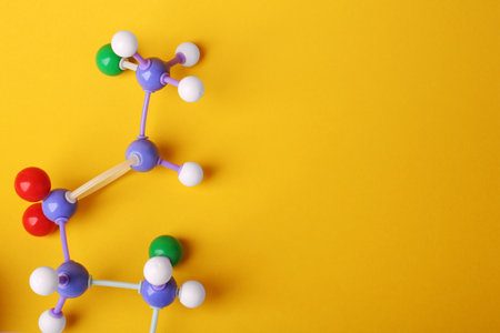 Structure of molecule on yellow background, top view and space for text. Chemical modelの写真素材