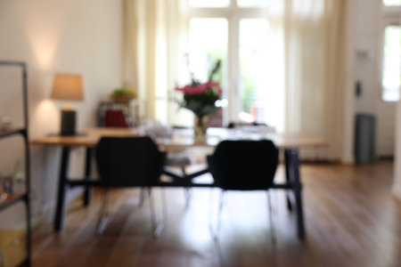 Stylish dining room with comfortable furniture, big window and bouquet of flowers, blurred viewの写真素材