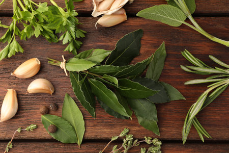 Aromatic bay leaves, different herbs and spices on wooden table, flat layの写真素材