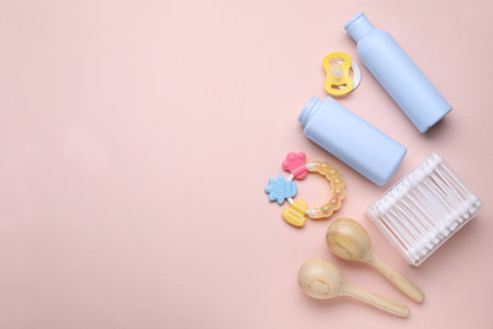 Different skin care products for baby, cotton buds, rattles and pacifier on light coral background, flat lay. Space for textの写真素材