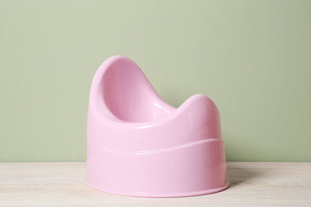 Pink baby potty on white wooden table against olive background. Toilet trainingの写真素材