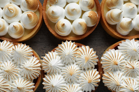 Many different tartlets with meringue on dark gray table, flat lay. Tasty dessertの写真素材